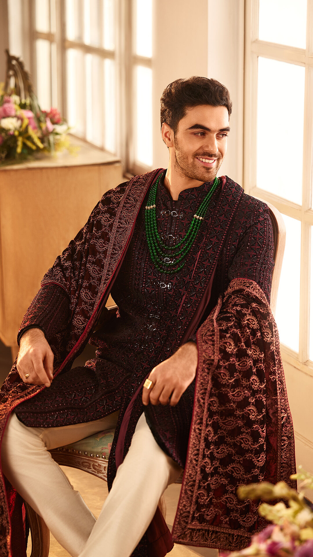 Man sitting on a chair, striking a pose in a luxurious velvet sherwani for a wedding photoshoot Man sitting on a chair, striking a pose in a luxurious velvet sherwani for a wedding photoshoot